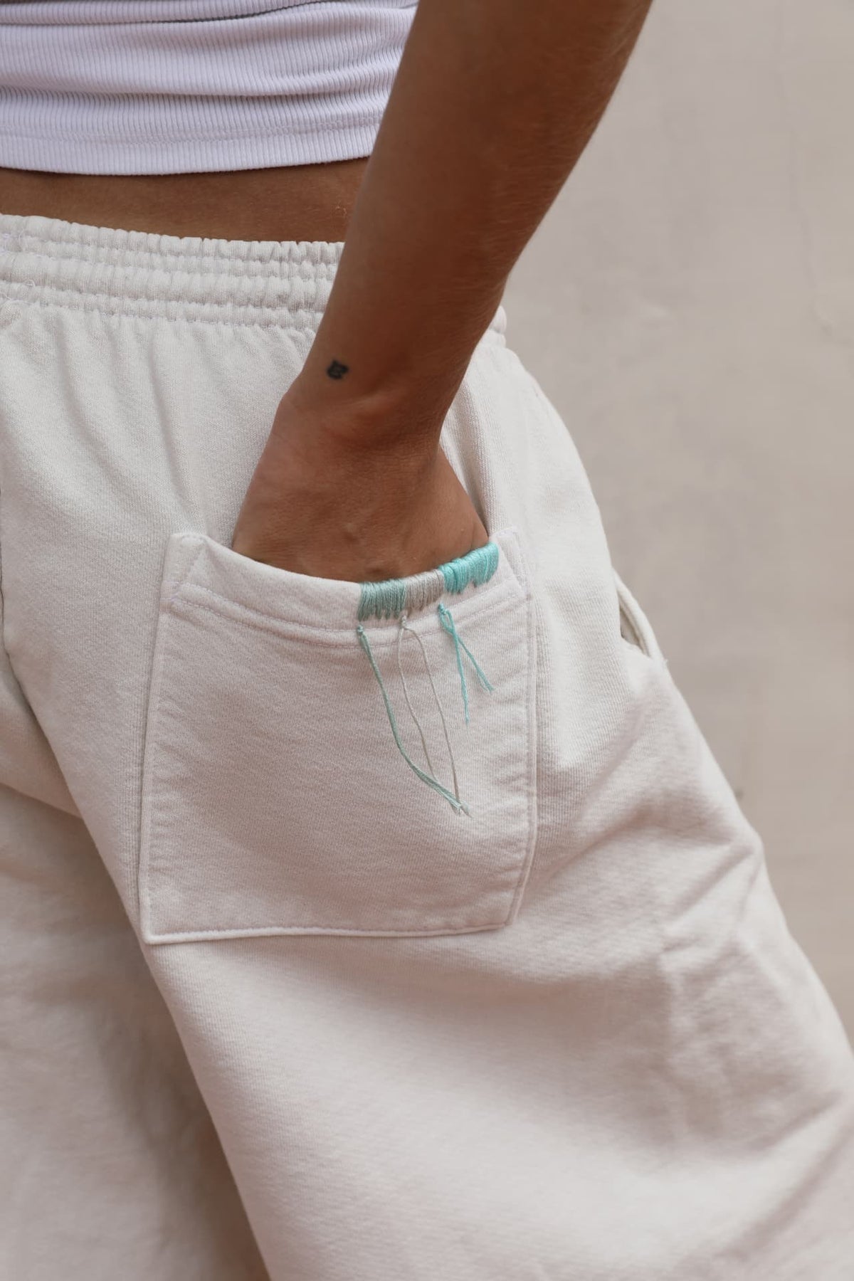 BELDI Ivory shorts · hand in pocket with turquoise embroidery